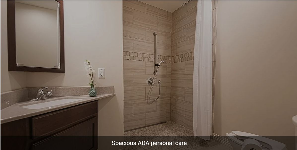 An accessible, spacious ADA-compliant shower with beige tiles and safety fixtures.