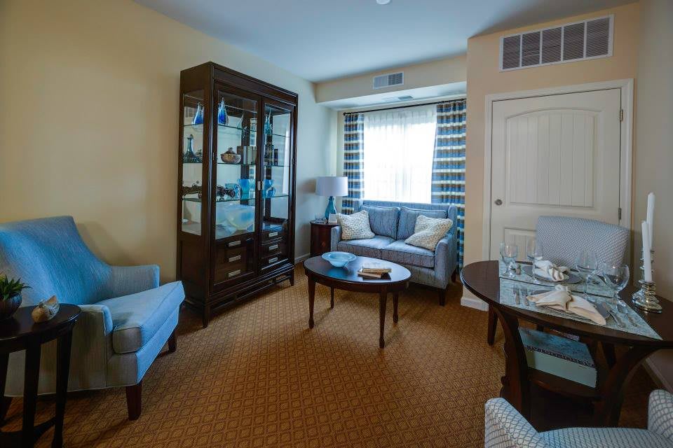 A cozy living room with a sofa, armchairs, a coffee table, and a display cabinet.
