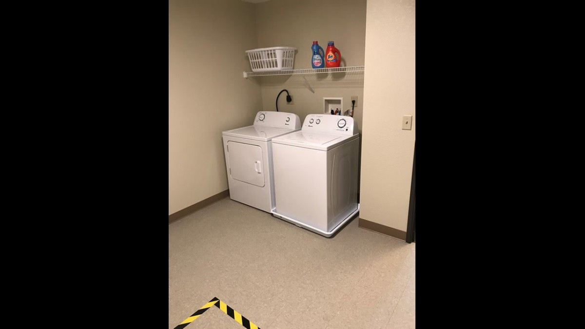A laundry room featuring a washing machine and dryer with detergent on a shelf above.