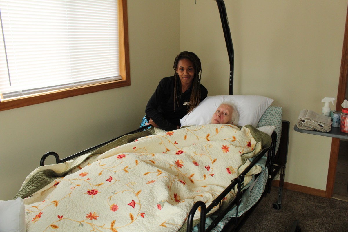 A caregiver attending to an elderly patient in a hospital bed.