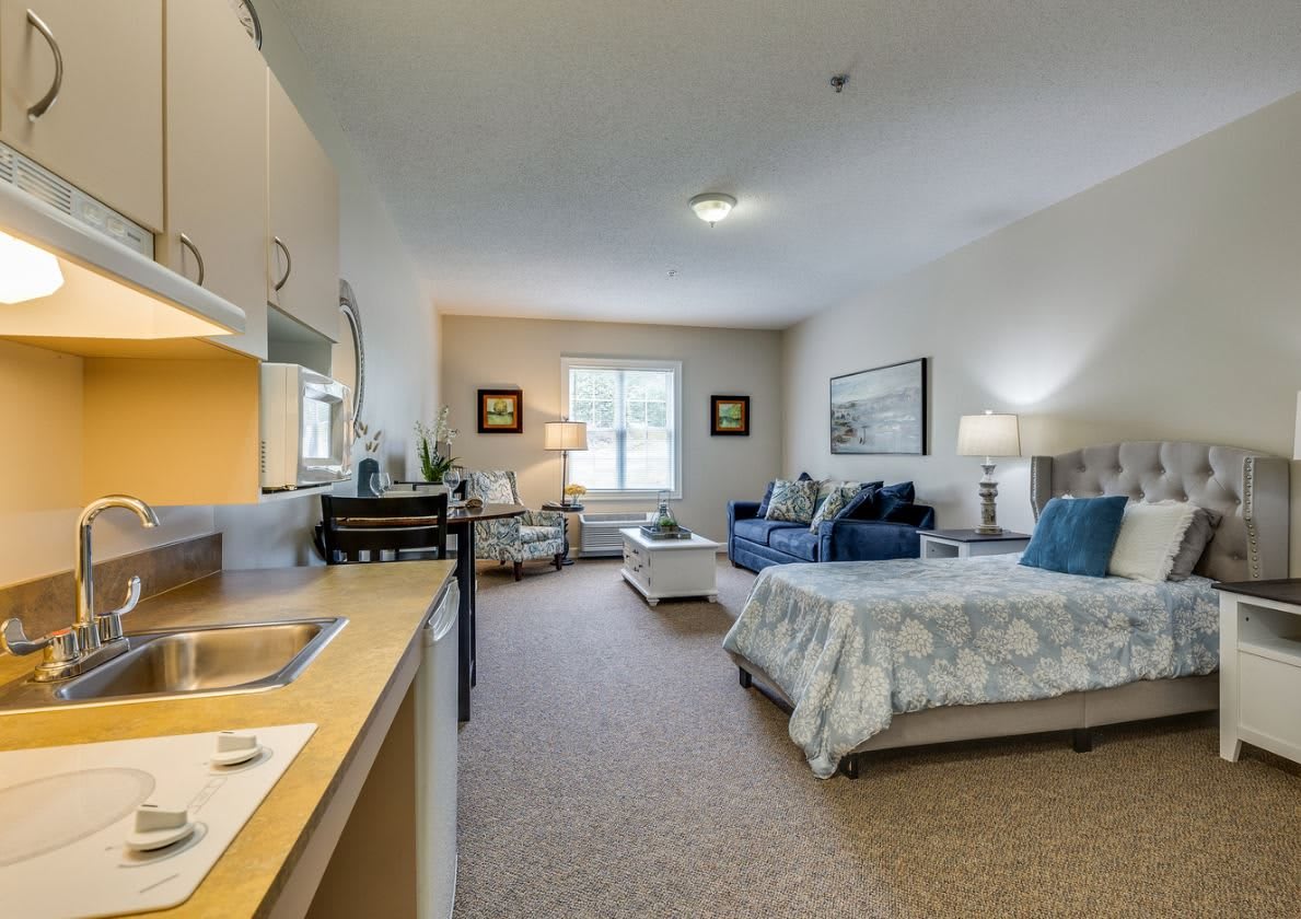 A cozy studio apartment with a combined living and sleeping area, featuring comfortable furniture and a small kitchenette.