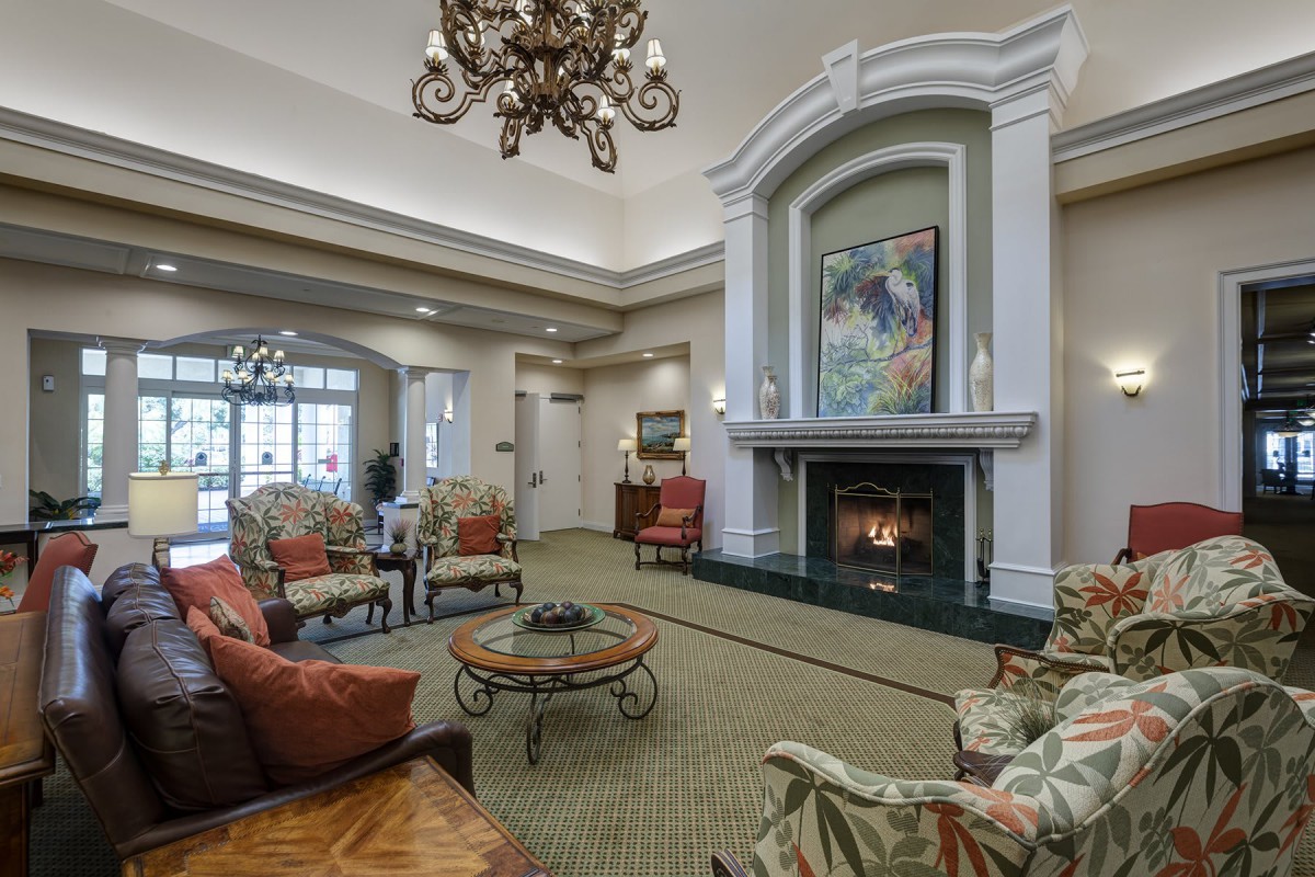 A cozy living room with a fireplace, elegant chandelier, and comfortable seating.