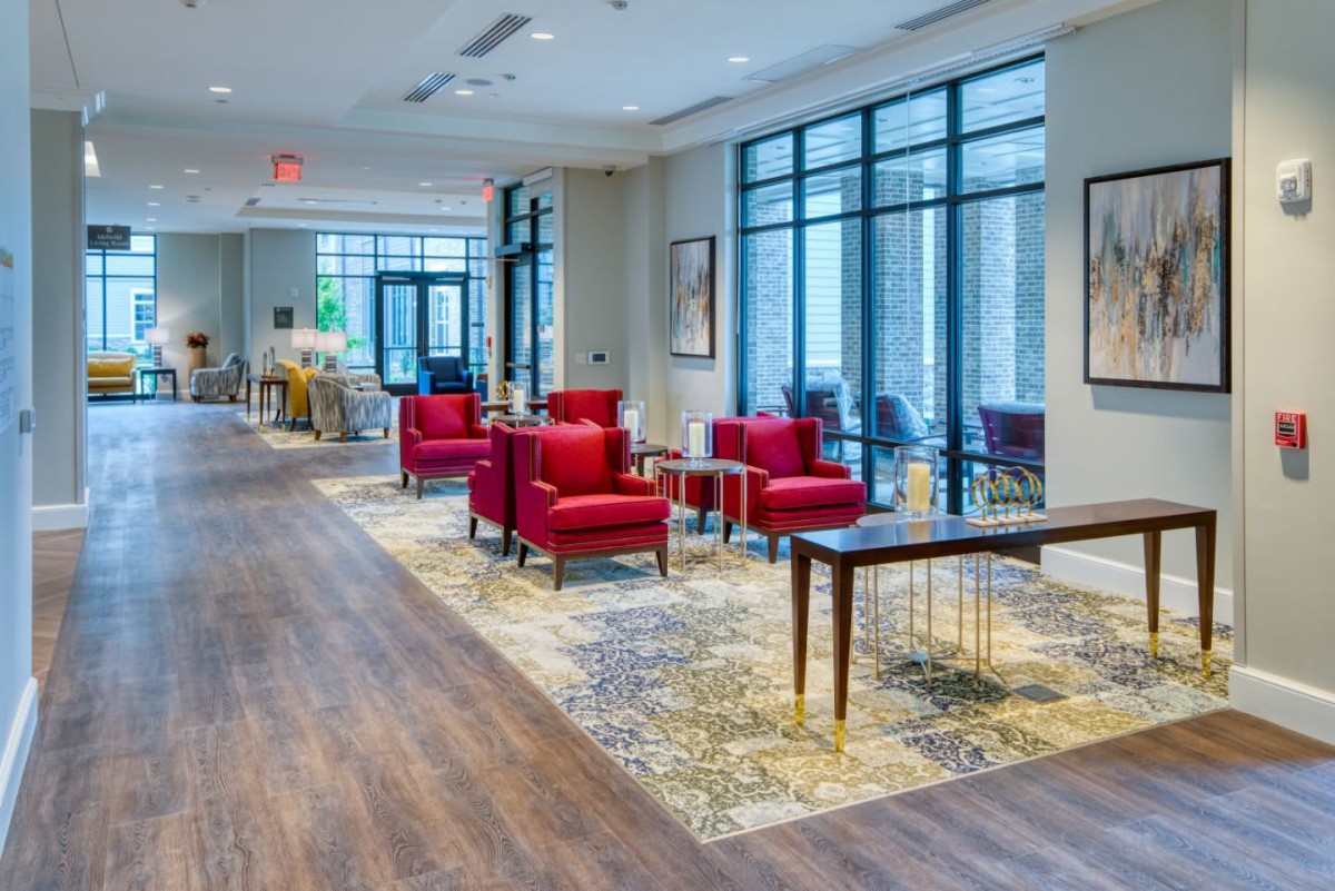 A modern lobby featuring red chairs and large windows, with artwork adorning the walls.