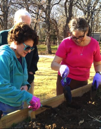 A group of people engaged in gardening, working together with soil in an outdoor setting.