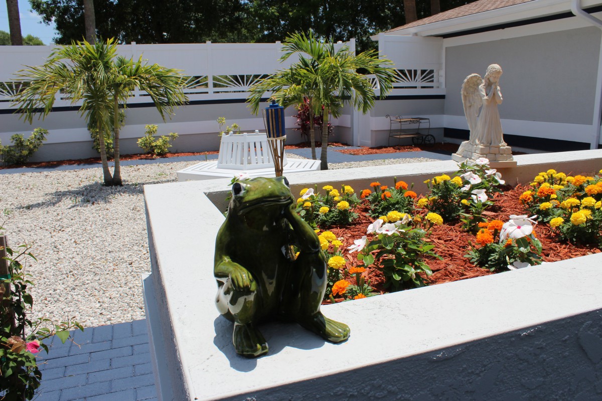 A garden with colorful flowers and a frog sculpture.