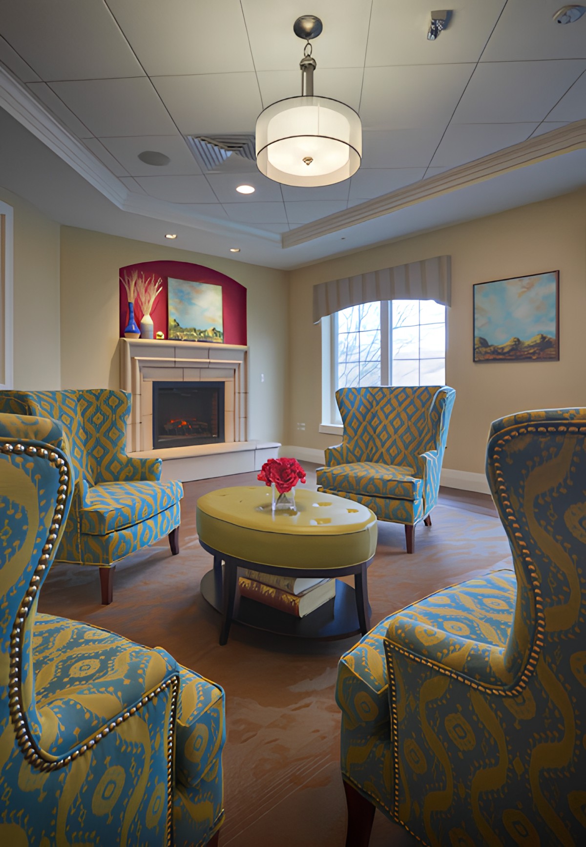 A cozy living room with patterned armchairs, a fireplace, and a circular table.