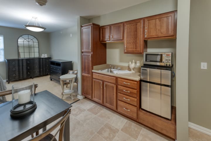 A cozy kitchen with wooden cabinets, a microwave, and a compact refrigerator, adjacent to a small dining area.