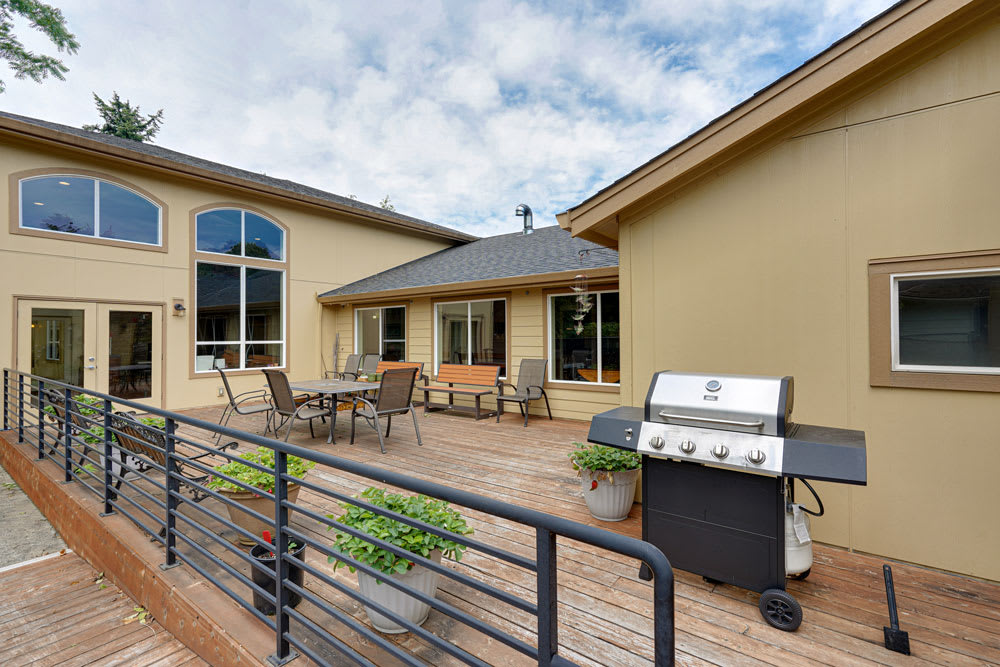 A spacious outdoor patio with a grill and seating area on a wooden deck.
