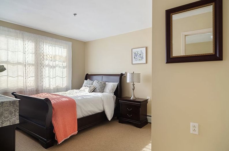 A cozy bedroom with a neatly made bed, nightstand, and decorative elements.