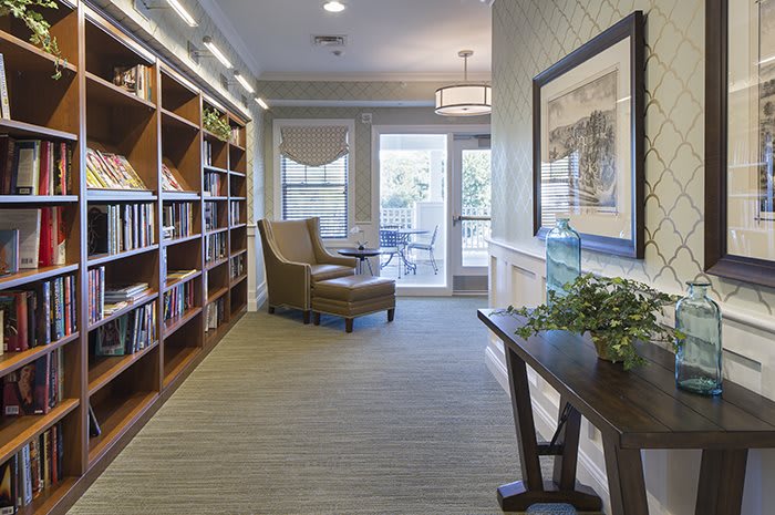 A cozy library interior featuring bookshelves, a reading chair, and ample natural light.