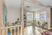 A bright and modern living room with ample natural light, featuring comfortable seating and decorative plants.