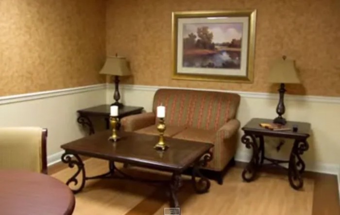 A cozy living room with a couch, tables, lamps, and a landscape painting.
