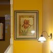 Framed floral artwork on a yellow-painted wall with a nearby light fixture.