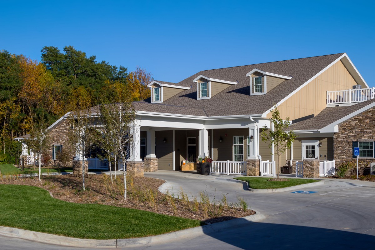 A suburban house with a porch and driveway on a sunny day.