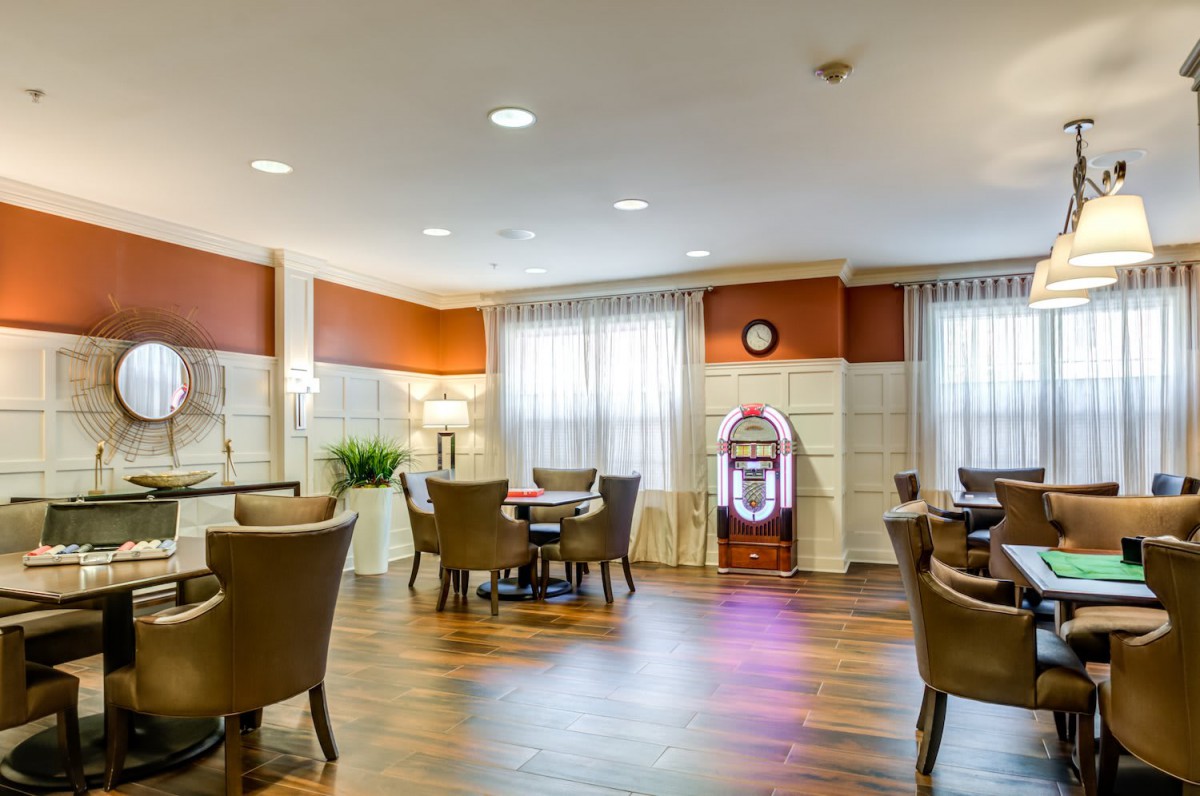 A cozy dining area with a jukebox, featuring comfortable chairs and tables on a wooden floor.