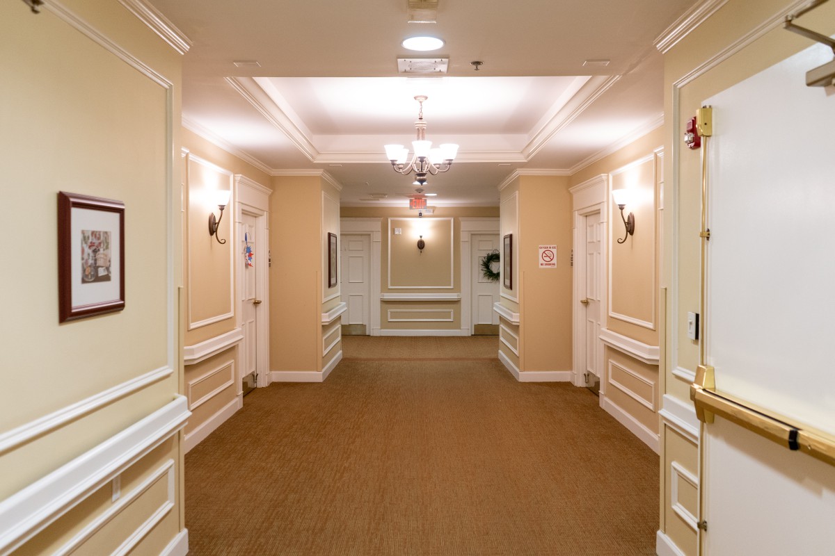 A well-lit hotel corridor with multiple doors and elegant decor.