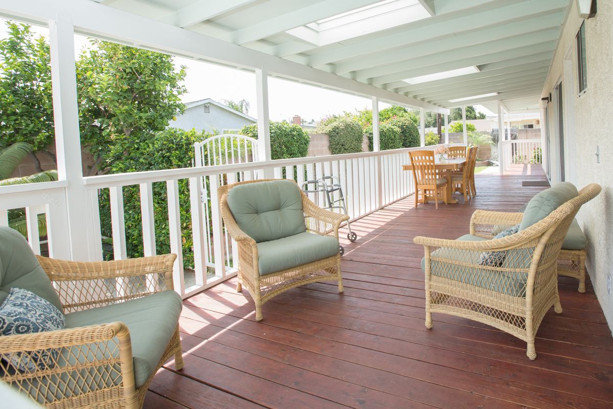 A cozy porch with wicker furniture and cushioned chairs, perfect for relaxing outdoors.