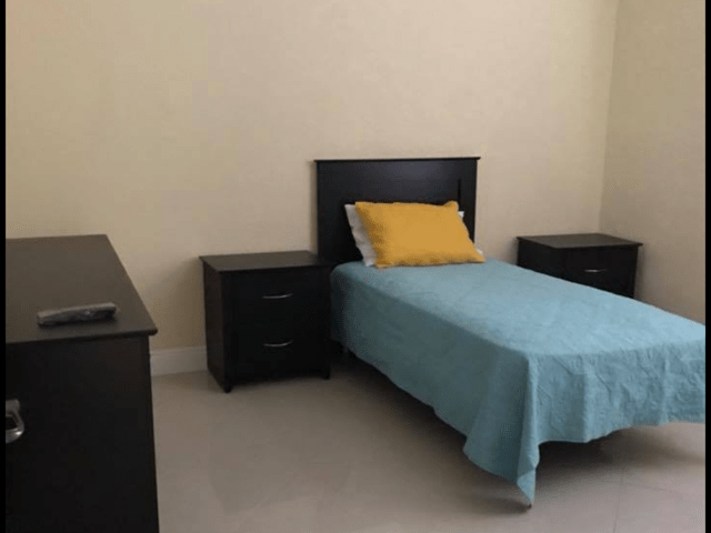 A minimalist bedroom with a single bed and matching furniture.