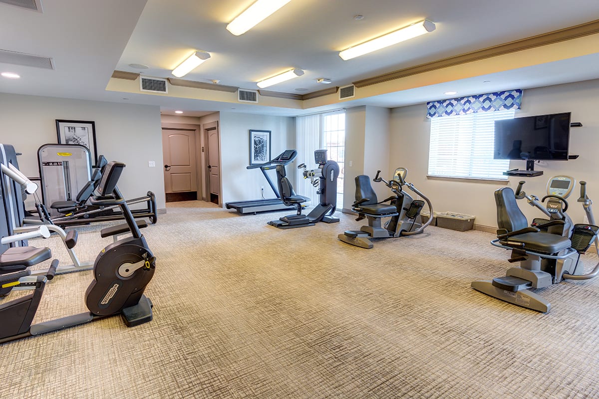 A small gym with various exercise equipment including treadmills and stationary bikes.
