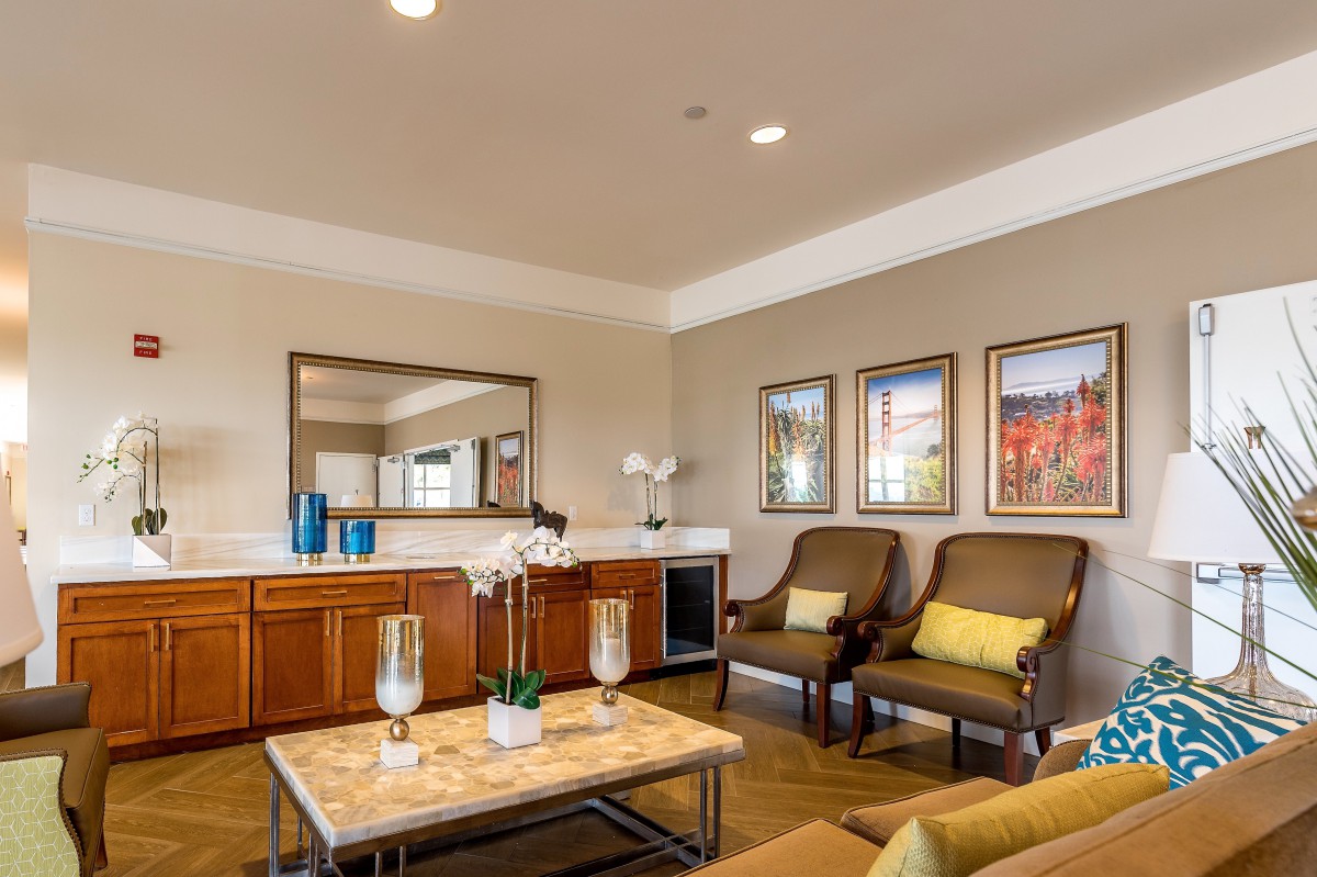 A well-decorated living room featuring elegant chairs, a coffee table with decorative items, and framed artwork on the walls.