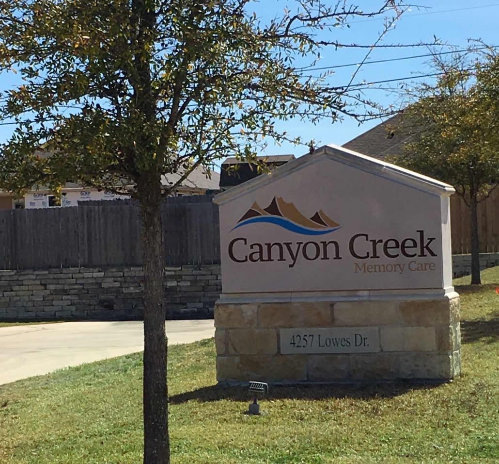 Entrance sign for the Canyon Creek neighborhood surrounded by trees and grass.