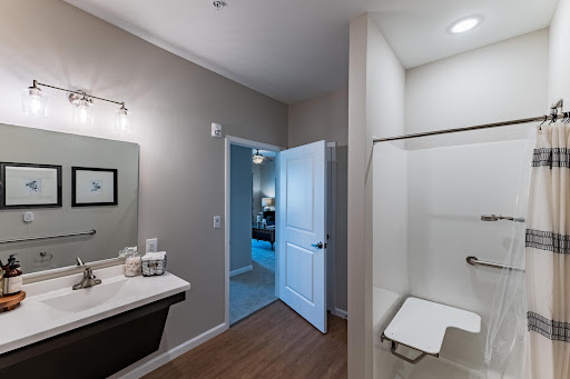 A modern bathroom featuring a sleek sink and shower, with an inviting door leading to another room.