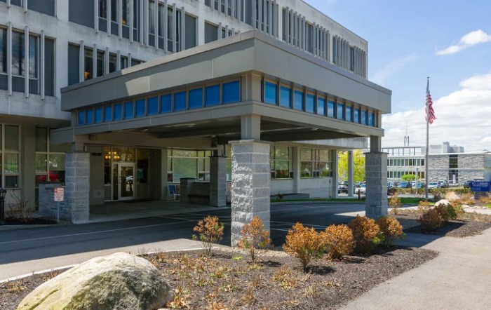 A modern office building with a landscaped entrance area on a clear day.