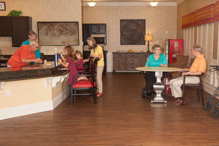 A group of people socializing in a cozy indoor setting with tables and chairs.