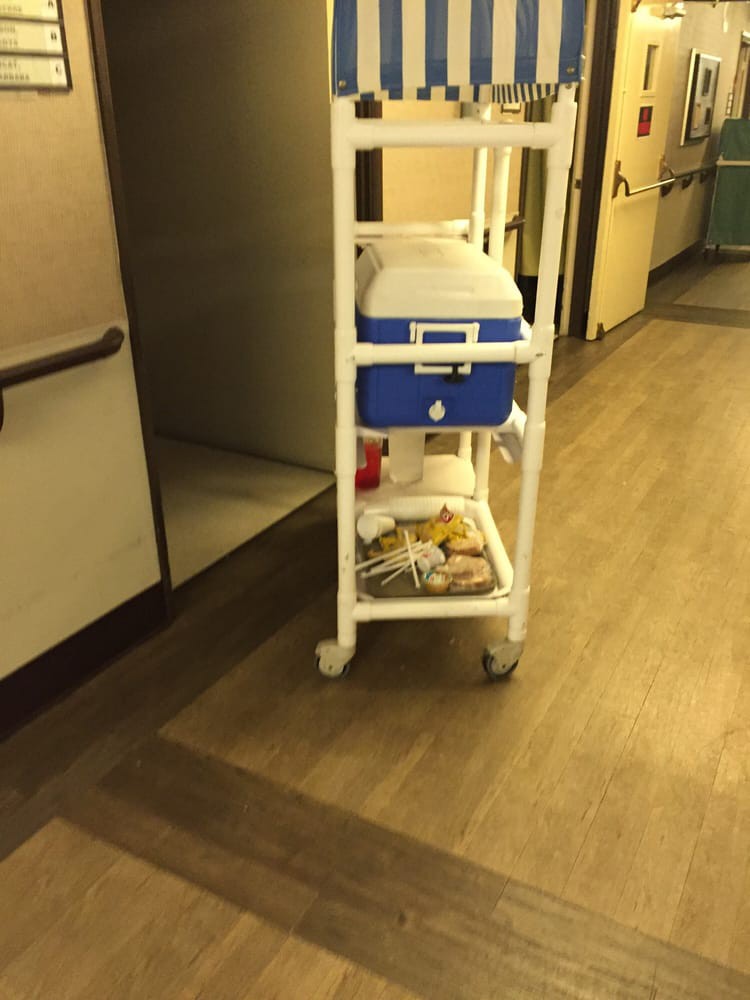 A hospital corridor with a medical cart and cooler.