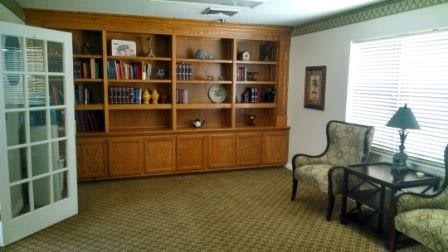 A cozy room with a large wooden bookshelf and a single armchair.