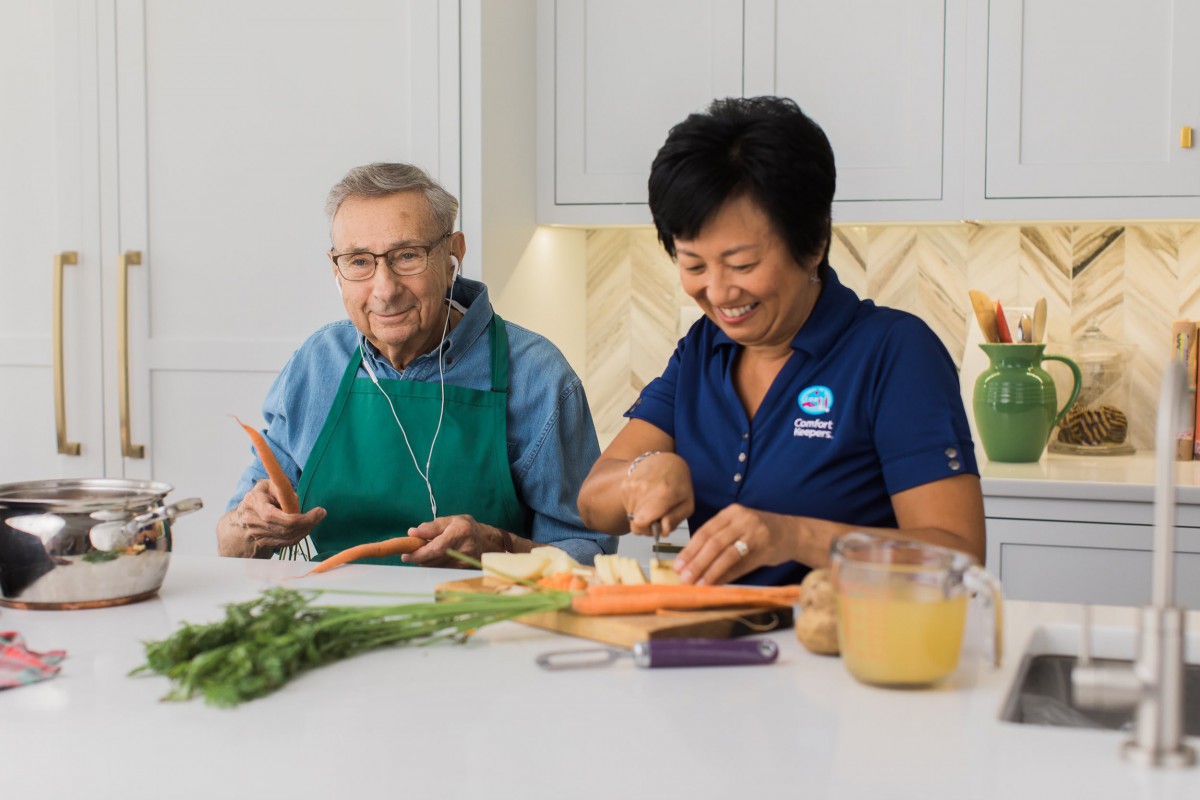 Two people preparing food together in a kitchen, focusing on cutting carrots.