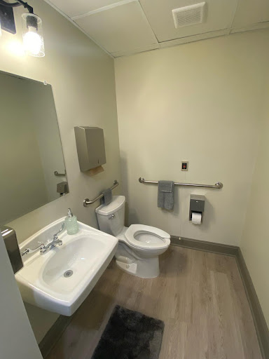 A clean and modern bathroom featuring a toilet, sink, and amenities.