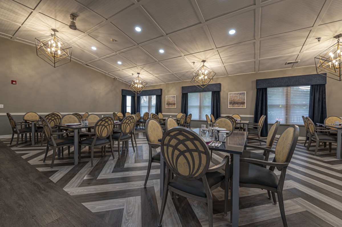 A well-arranged dining room featuring elegantly set tables and chairs with ceiling lights and patterned flooring.