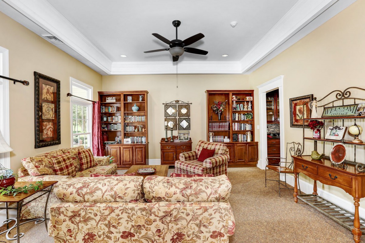 A cozy living room with traditional decor, featuring patterned sofas, armchairs, and wooden bookshelves.