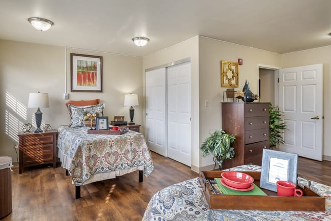 A cozy bedroom with two beds, decorated with patterned bedding and featuring wooden floors.