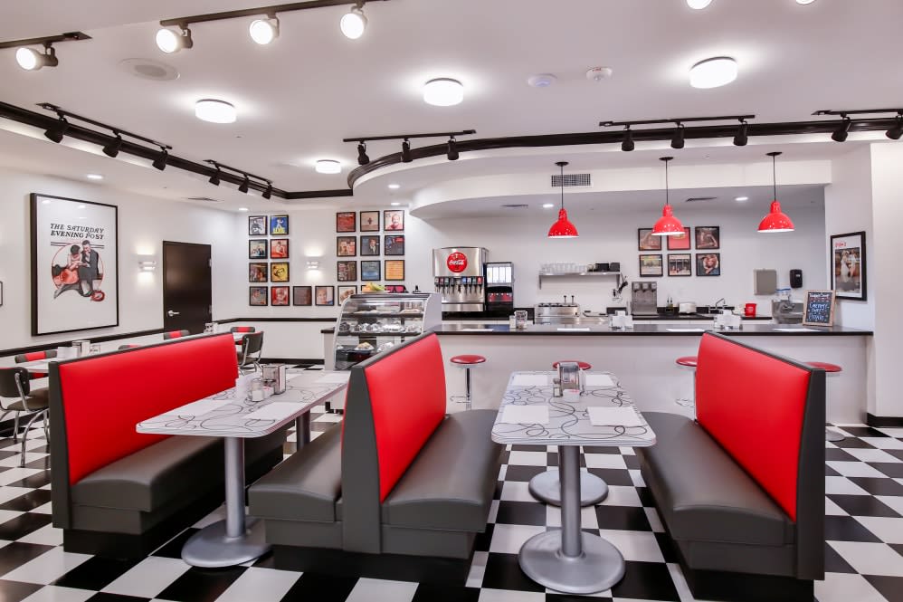 A retro-style diner with red booth seating and a classic black-and-white checkered floor.