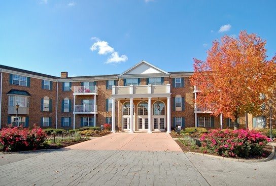 A residential building surrounded by autumn trees under a clear blue sky.