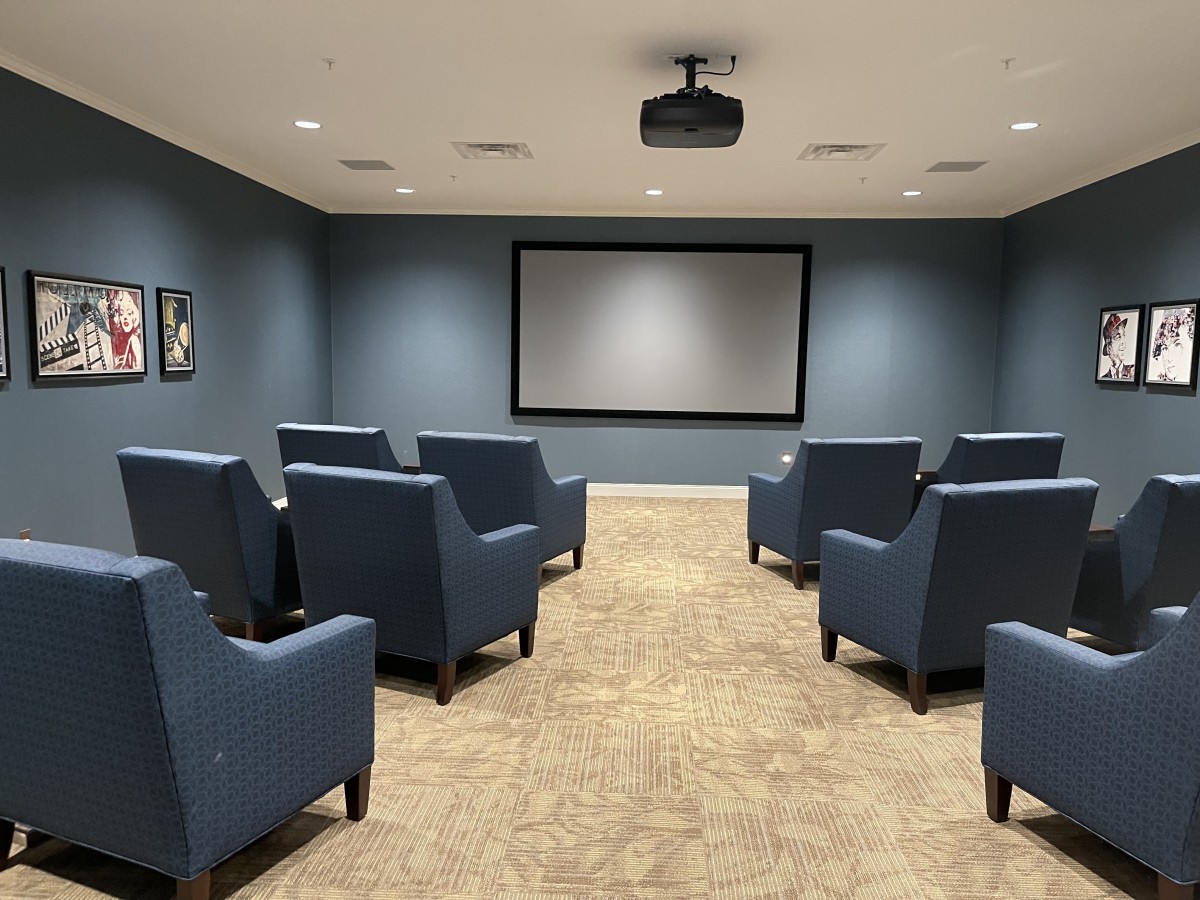 A cozy home theater setup with multiple chairs facing a large screen.