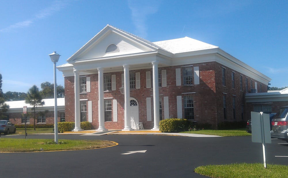 A classic-style brick building with large white columns and a triangular pediment.