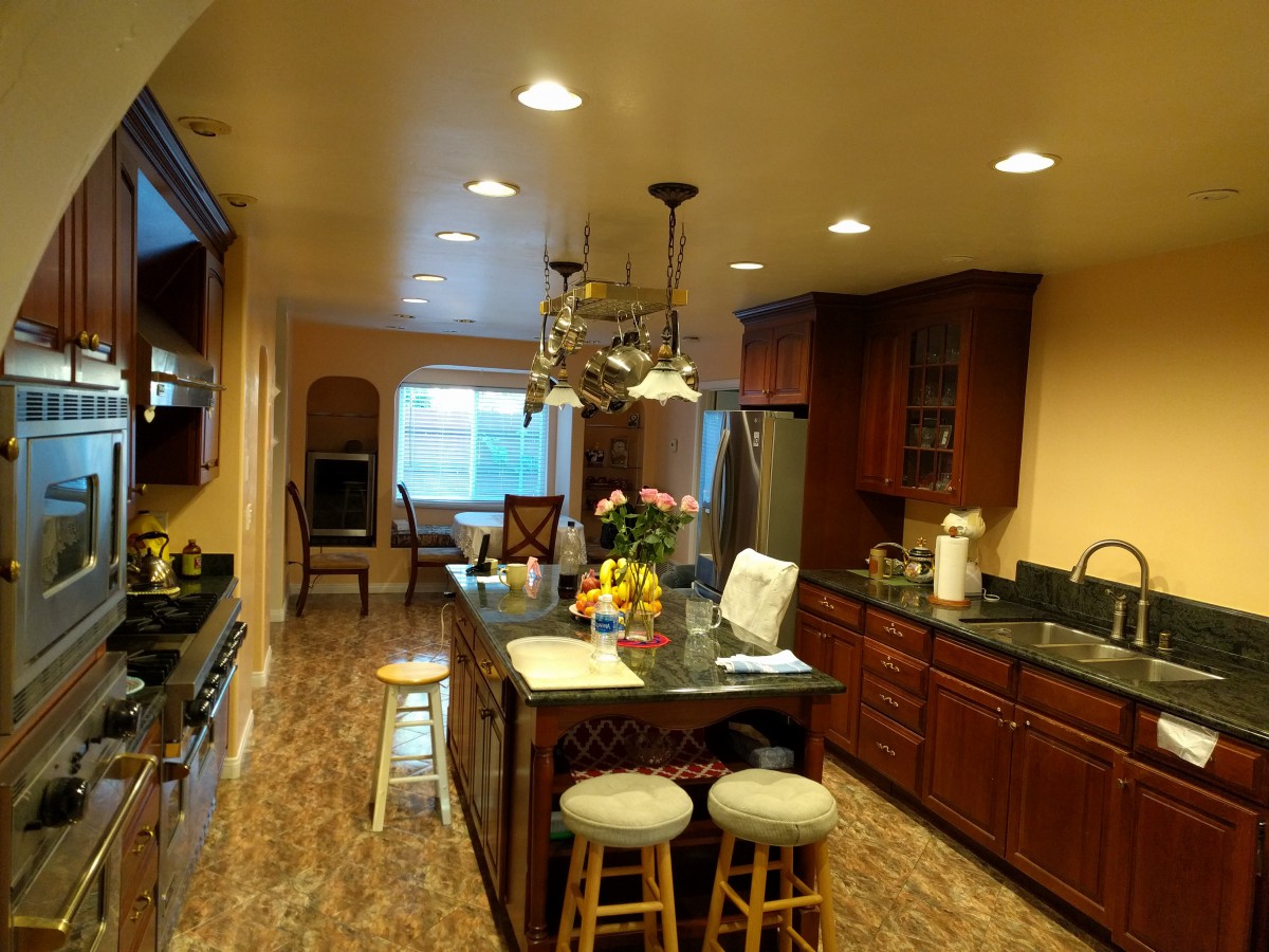 A spacious kitchen with dark wood cabinets, an island with seating, and modern lighting.