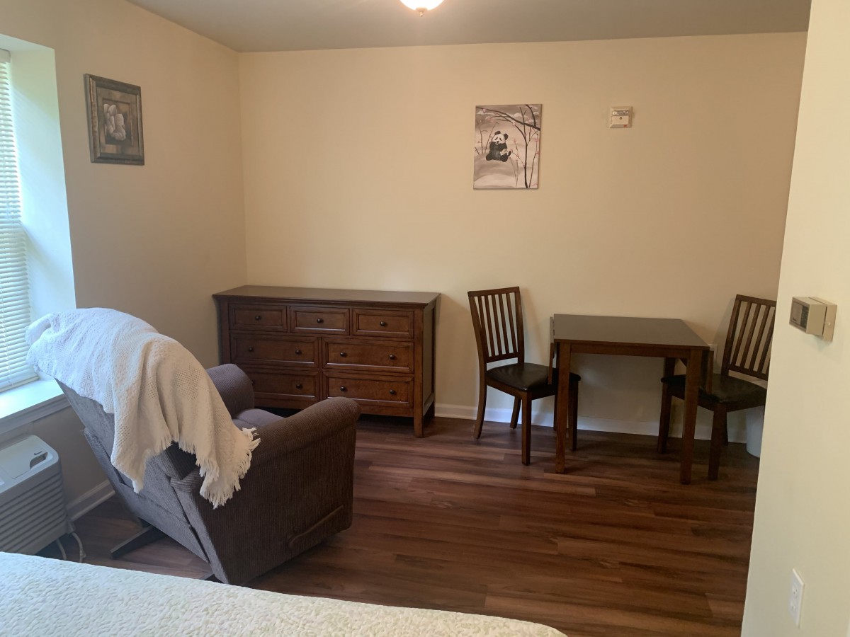 A cozy living room with wooden furniture including a dresser, table, and chairs.