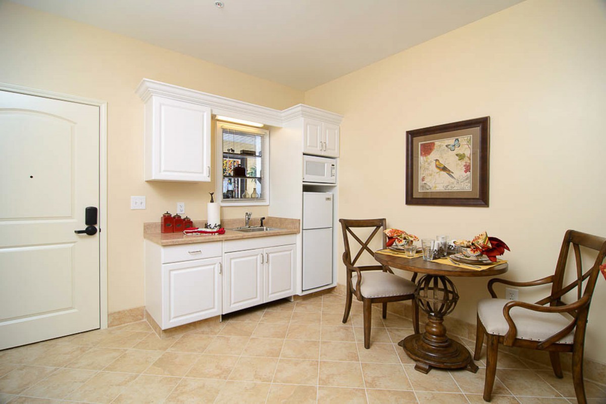 A cozy kitchen and dining area with white cabinets, a small round table, and two chairs.