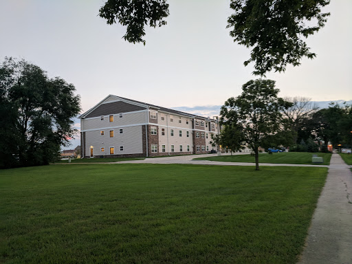 A modern building set against a serene evening sky, surrounded by lush green grass and trees.