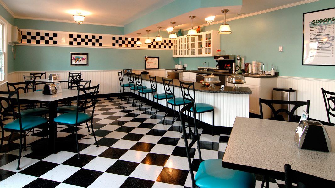 A retro-style diner with teal bar stools and a black-and-white checkerboard floor.