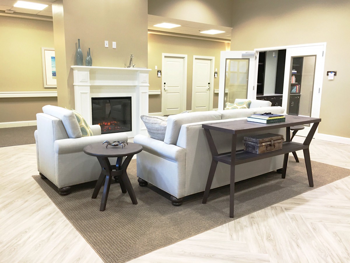 A modern living room with a cozy fireplace, featuring light-colored sofas and a wooden coffee table.