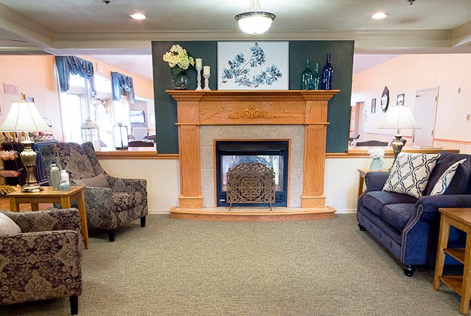 A cozy living room featuring a central fireplace with decorative elements on the mantel, surrounded by comfortable seating.