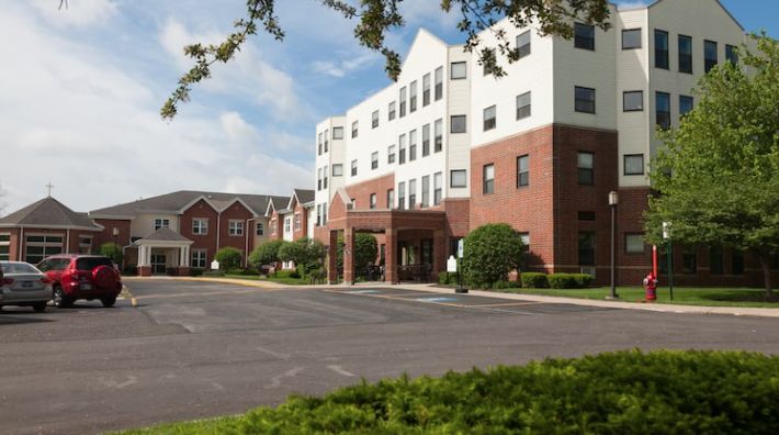 A view of a healthcare facility with a spacious parking area and landscaped surroundings.