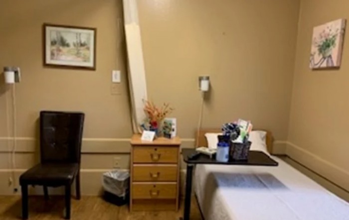 A hospital room with a bed, nightstand, and decor.