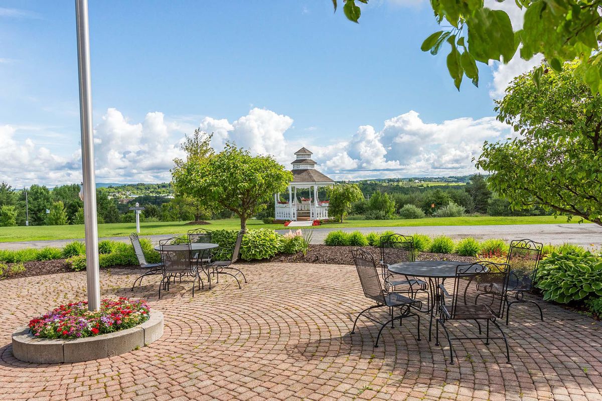 A scenic patio with outdoor seating overlooking a lush landscape and a gazebo in the distance.