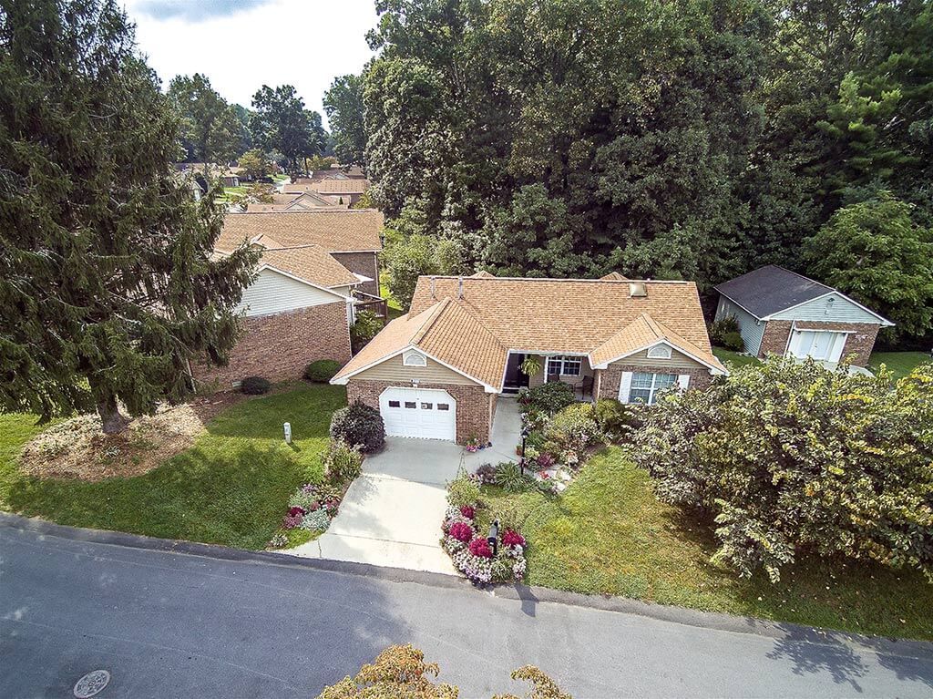 Aerial view of a suburban house with a driveway and surrounding greenery.